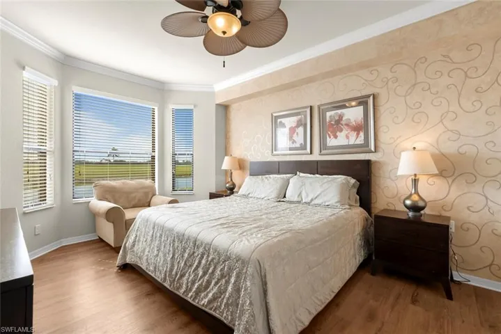 Bedroom with ceiling fan, crown molding, and wood-type flooring