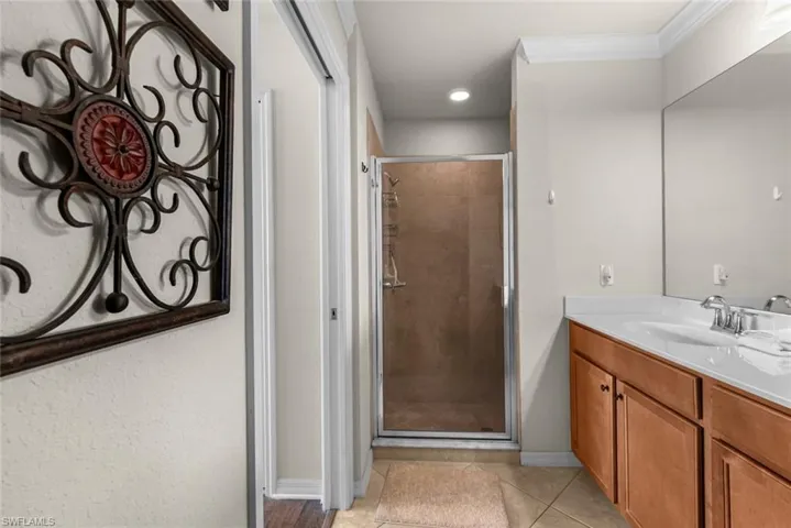 Bathroom featuring ornamental molding, tile patterned floors, walk in shower, and vanity