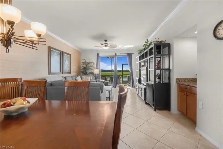 Dining space featuring ceiling fan, light tile patterned flooring, and crown molding