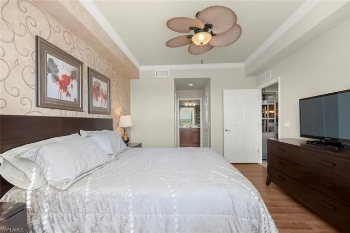 Bedroom featuring ensuite bathroom, ornamental molding, ceiling fan, and light hardwood / wood-style floors