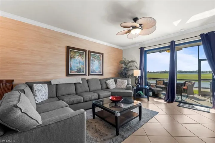 Living room with ceiling fan, a water view, crown molding, and light tile patterned floors