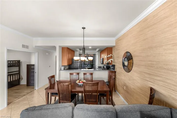 Tiled dining area featuring ornamental molding and an inviting chandelier