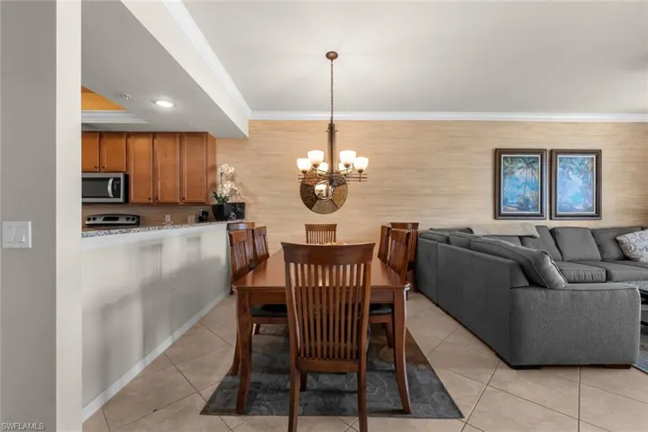 Tiled dining area featuring an inviting chandelier and ornamental molding
