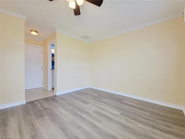 Empty room featuring crown molding, light wood-style flooring, and ceiling fan