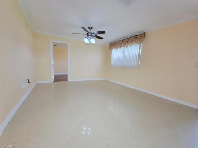 Spare room with crown molding, light tile patterned floors, and ceiling fan