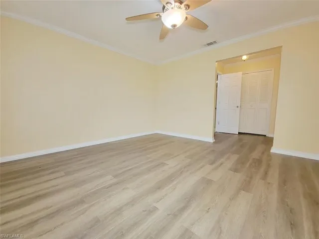 Unfurnished room with crown molding, light wood finished floors, and ceiling fan