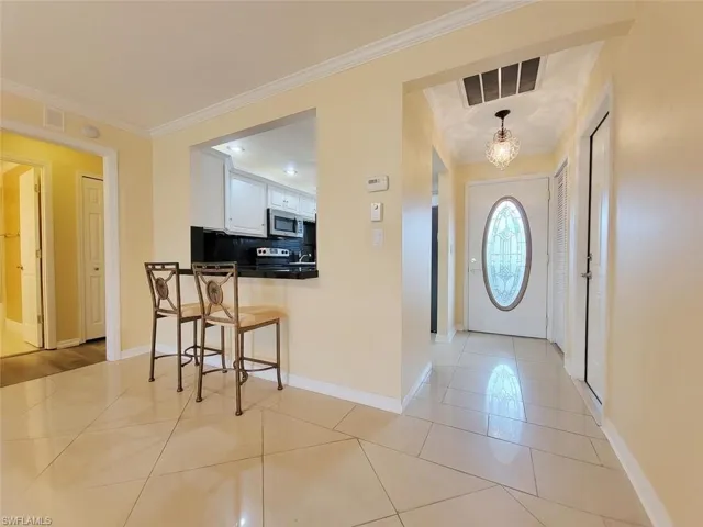 Entrance foyer with crown molding and light tile patterned floors