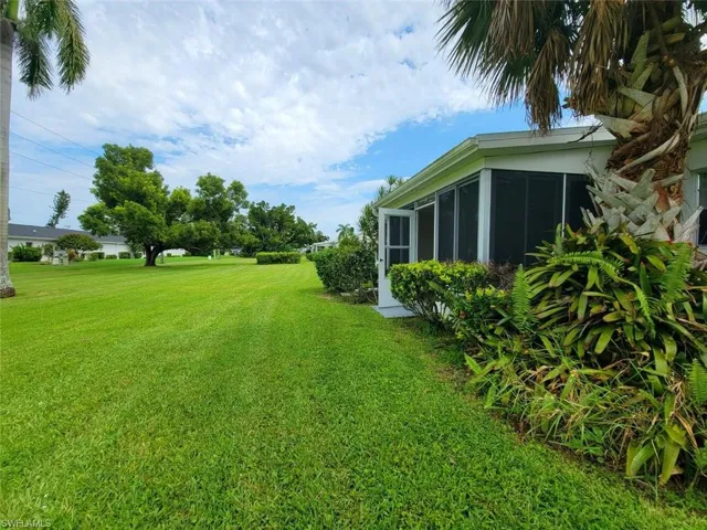 View of grassy yard with a sunroom