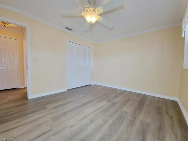 Unfurnished bedroom with ornamental molding, light wood-type flooring, a ceiling fan, and a closet