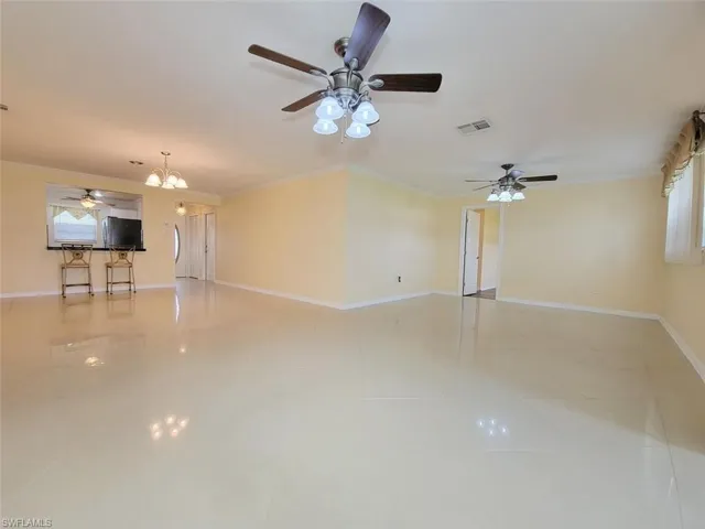 Unfurnished living room with ceiling fan, crown molding, a chandelier, and light tile patterned floors