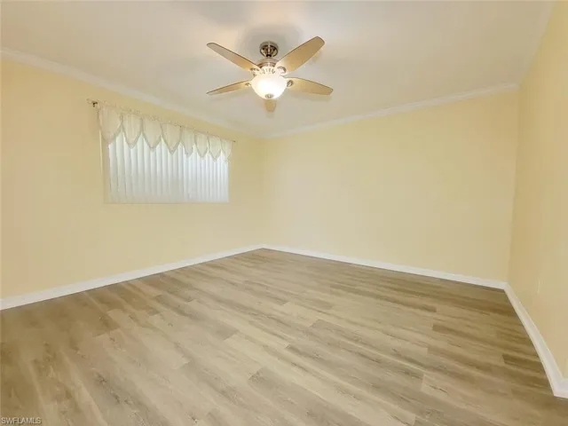 Empty room featuring crown molding, light wood finished floors, and ceiling fan