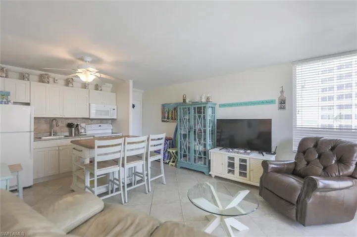 Living room featuring ceiling fan, light tile patterned flooring, and expansive windows