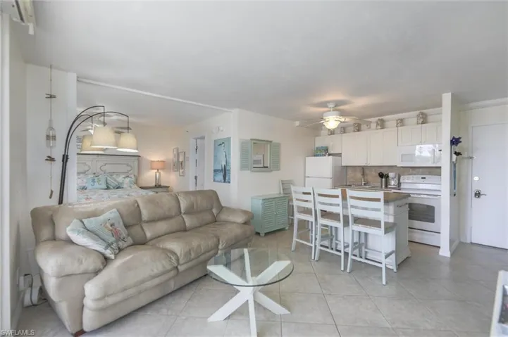Kitchen with light tile patterned floors, white appliances, tasteful backsplash, a ceiling fan, and a sink