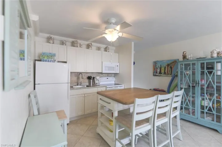 Kitchen with light tile patterned floors, baseboards, floor to ceiling windows, open floor plan, and ceiling fan