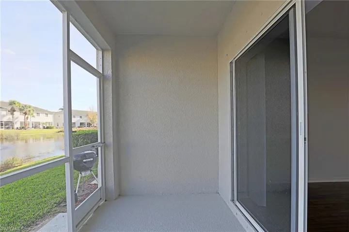 Unfurnished sunroom featuring a water view, a textured wall, and a residential view