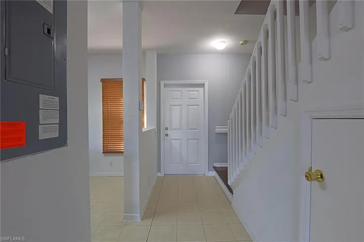 Foyer entrance with electric panel, light tile patterned flooring, and a textured ceiling