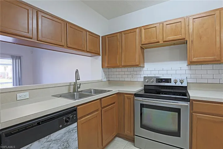 Kitchen with stainless steel electric range, dishwasher, light countertops, wood finish cabinets, and decorative backsplash