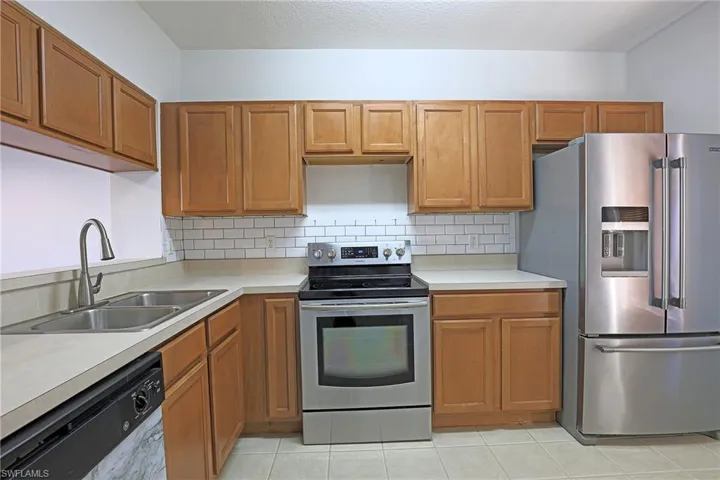Kitchen featuring stainless steel appliances, light countertops, wood finish cabinets, and a textured ceiling