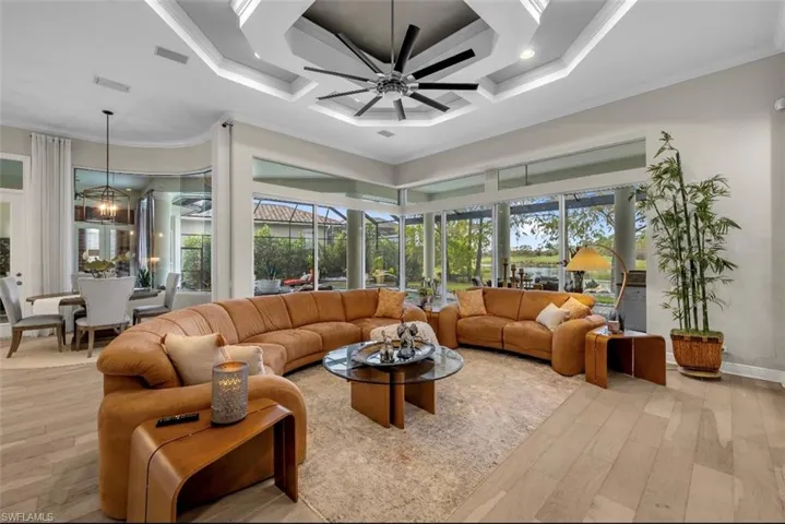 Living area with a ceiling fan, coffered ceiling, a high ceiling, light wood-style floors, and plenty of natural light