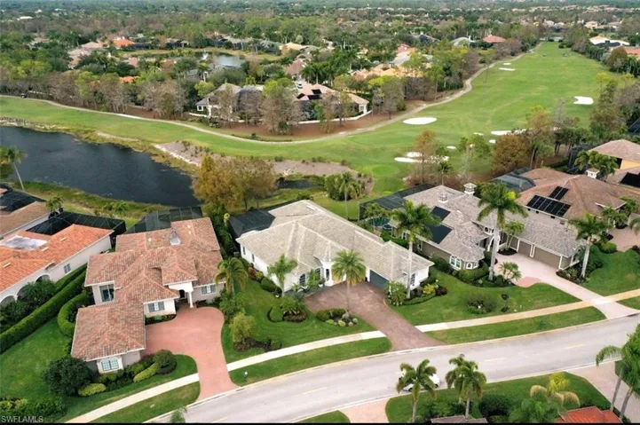 Aerial view of property and surrounding area featuring nearby suburban area, a nearby body of water, and a local golf course