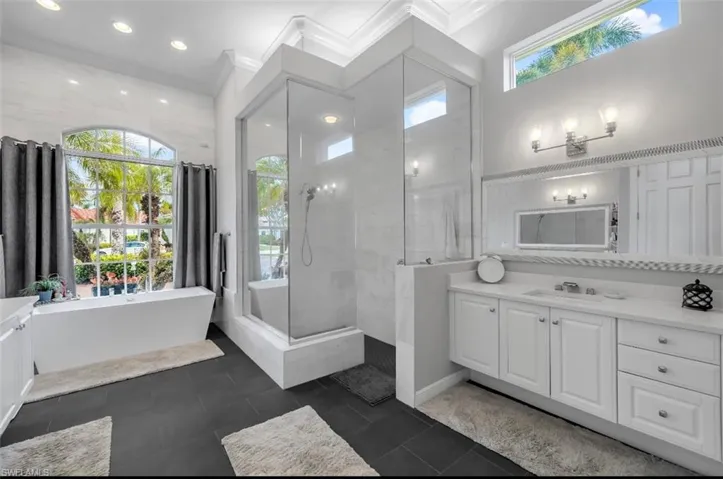 Full bath with vanity, plenty of natural light, a tile shower, a freestanding tub, and ornamental molding