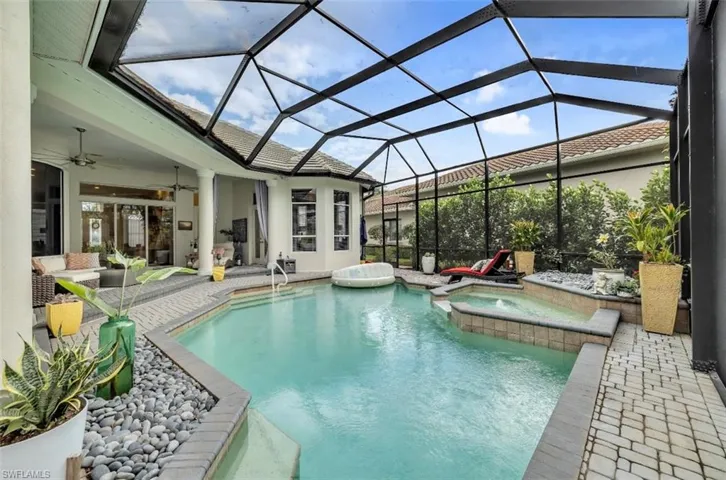 View of pool featuring a sunroom, a patio, glass enclosure, and a pool with connected hot tub