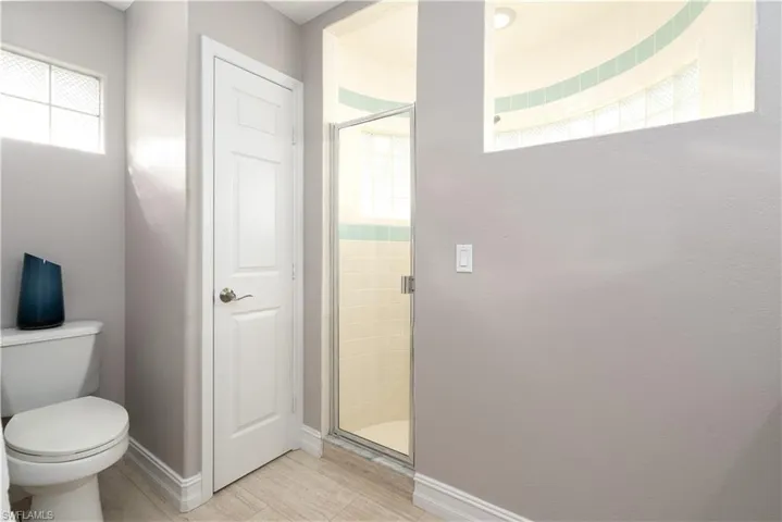 Bathroom with a shower with shower door, toilet, and a healthy amount of sunlight