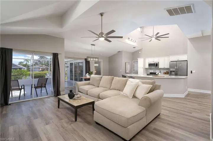 Living room with ceiling fan, vaulted ceiling, and light hardwood / wood-style flooring