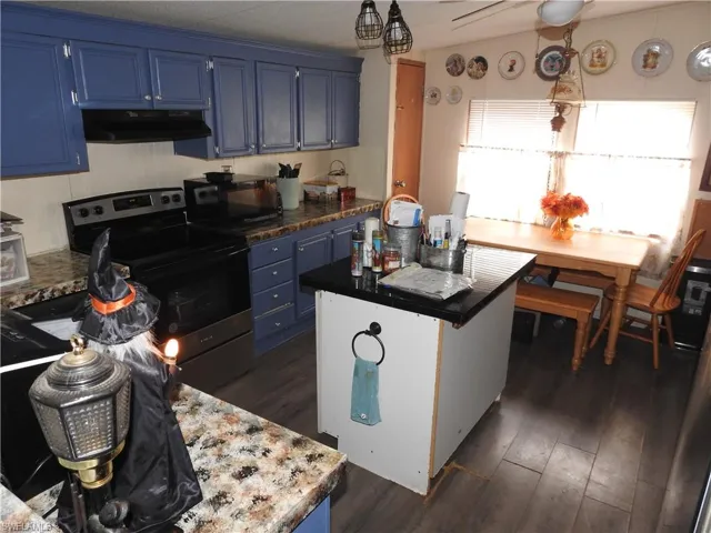 Kitchen featuring blue cabinets, dark wood-type flooring, a center island, and stainless steel electric range