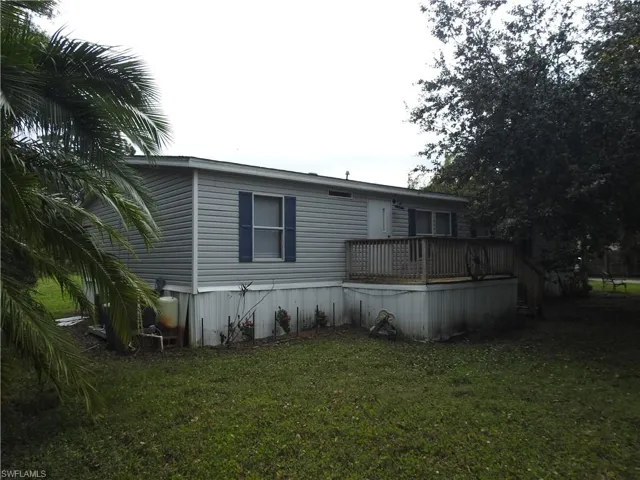 Rear view of house with a deck and a lawn