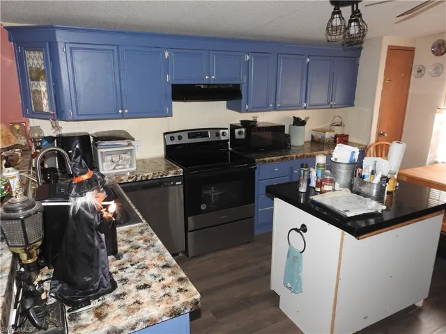 Kitchen with appliances with stainless steel finishes, a textured ceiling, dark hardwood / wood-style floors, range hood, and blue cabinets