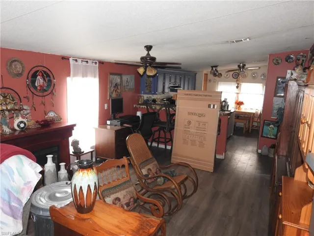 Living room featuring a textured ceiling, ceiling fan, a fireplace, and dark hardwood / wood-style flooring
