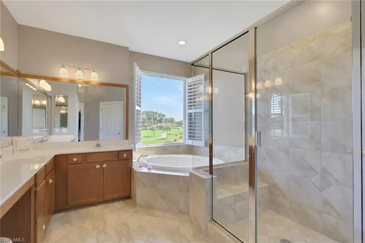 Bathroom with a garden tub, a shower stall, double vanity, light tile patterned floors, and recessed lighting