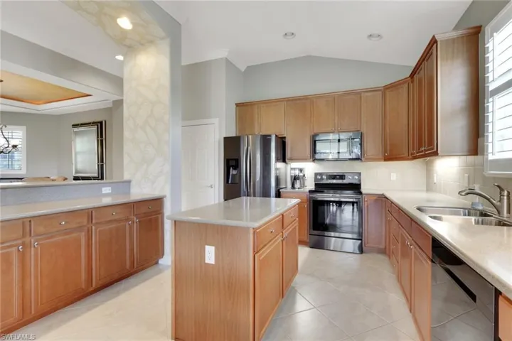 Kitchen featuring healthy amount of natural light, stainless steel appliances, decorative backsplash, a center island, and crown molding