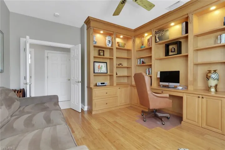 Office area with built in study area, light wood finished floors, ceiling fan, and built in features