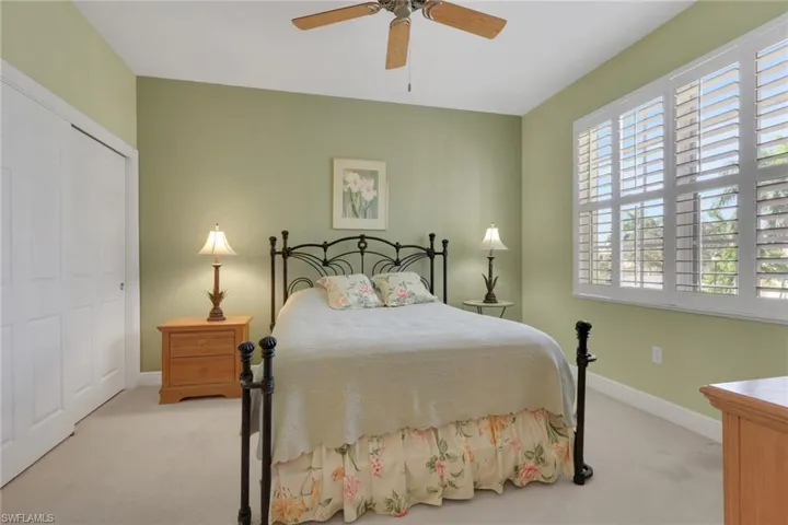 Bedroom featuring light colored carpet, ceiling fan, and a closet
