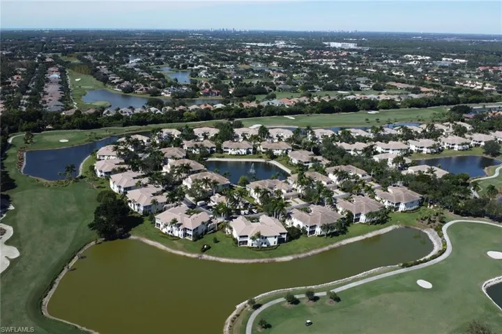 Aerial view of property's location featuring a golf course and nearby suburban area