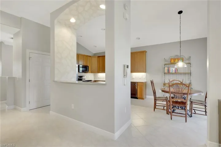 Kitchen featuring lofted ceiling, tasteful backsplash, decorative light fixtures, arched walkways, and recessed lighting