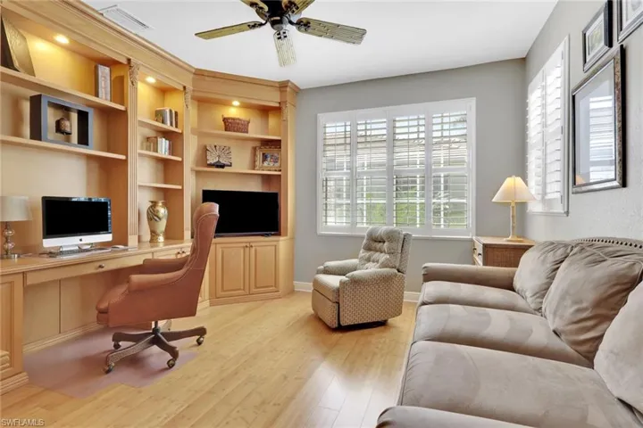 Home office with built in study area, ceiling fan, and light wood finished floors