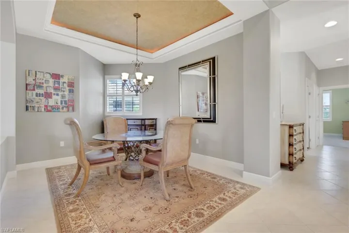 Dining space featuring a tray ceiling, a chandelier, and light tile patterned flooring