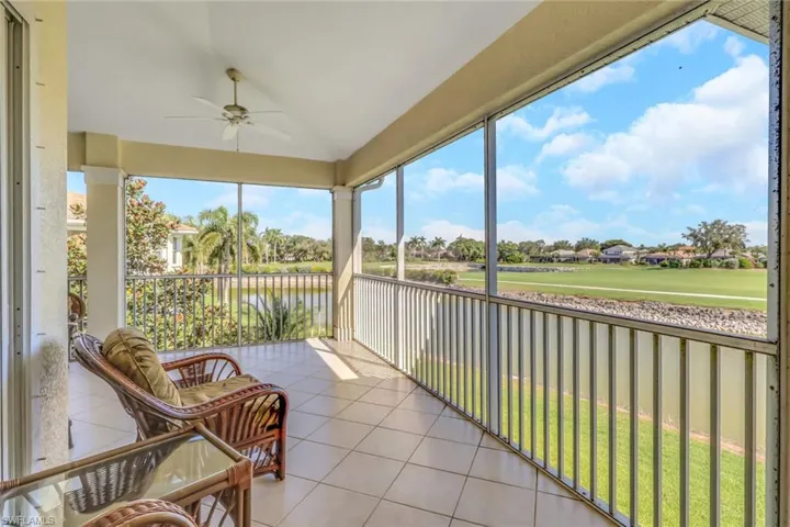 Sunroom featuring lofted ceiling, ceiling fan, a water view, and a balcony