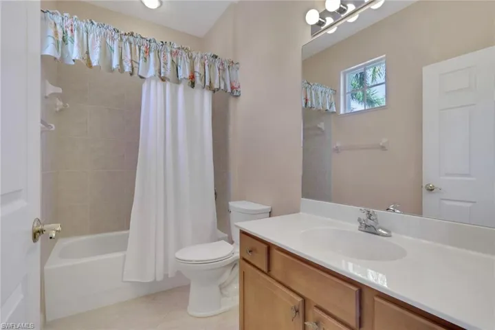 Bathroom featuring shower / tub combo with curtain, vanity, and light tile patterned floors