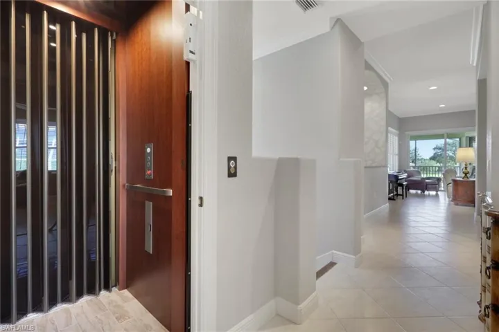 Hall with elevator, light tile patterned flooring, and ornamental molding