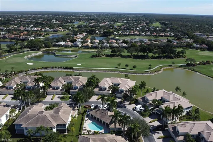 Aerial view of residential area featuring a golf club and a nearby body of water