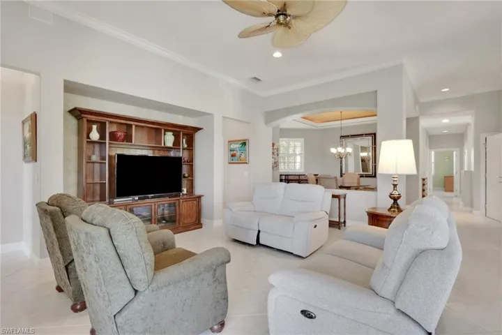 Living room with light tile patterned flooring, crown molding, a chandelier, recessed lighting, and ceiling fan