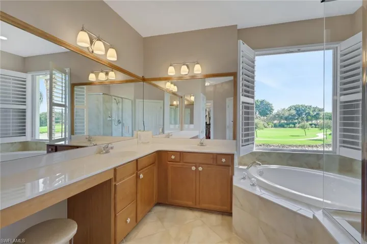 Bathroom with a bath, double vanity, a stall shower, and light tile patterned flooring