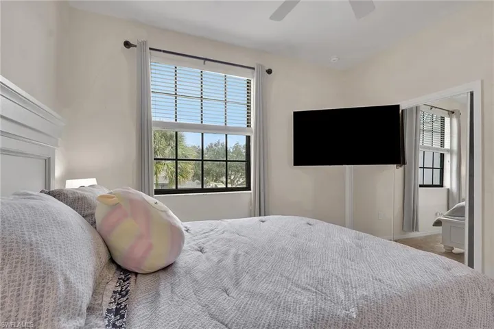 Multi-pane windows with black frames, ceiling-mounted fan, and mirrored closet doors