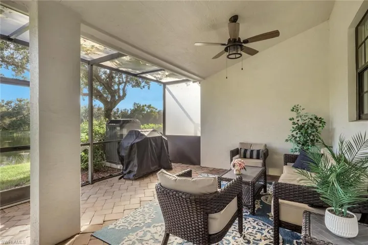 Screened-in covered patio featuring brick paver flooring and a ceiling-mounted fan