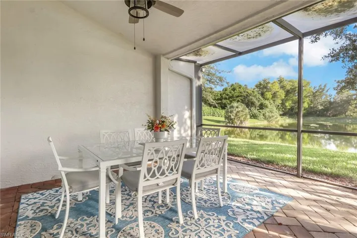 Screen-enclosed patio featuring paver flooring, a ceiling fan, and exterior water backdrop