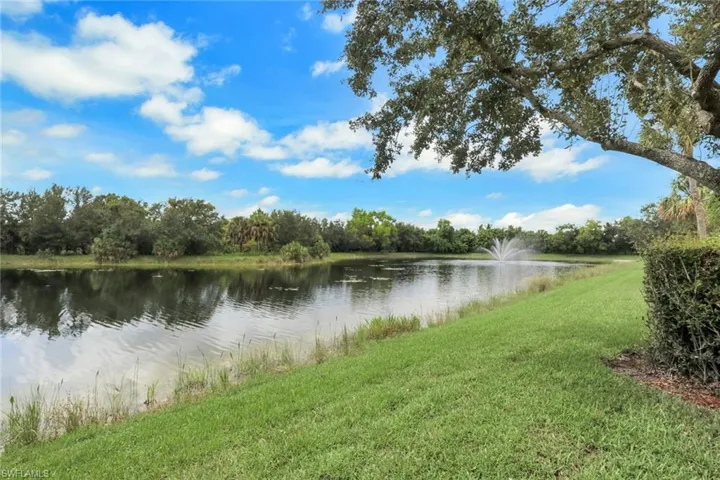 Waterfront parcel featuring a manicured lawn, established shade trees, a pond, and a built-in fountain